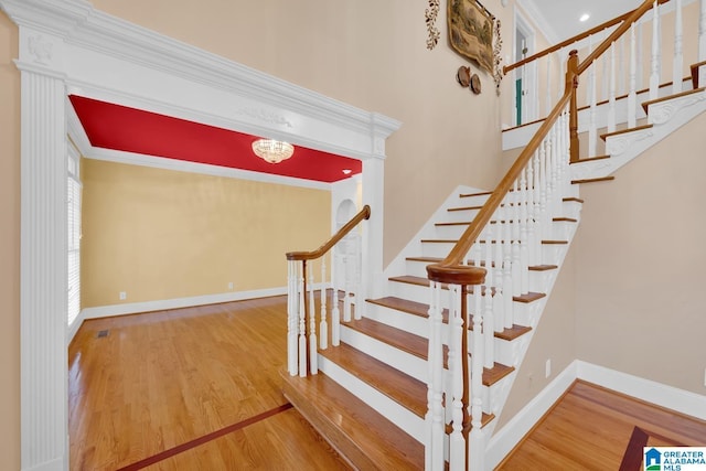 stairs with crown molding and wood-type flooring