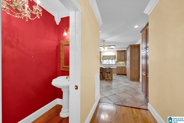 hallway with crown molding and light hardwood / wood-style flooring