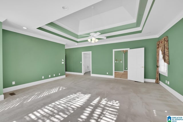 carpeted spare room with a raised ceiling, ceiling fan, and crown molding