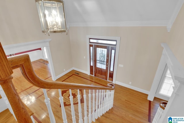 foyer featuring hardwood / wood-style floors, crown molding, a wealth of natural light, and a notable chandelier