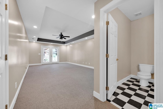 interior space with a tray ceiling, ceiling fan, french doors, and carpet floors