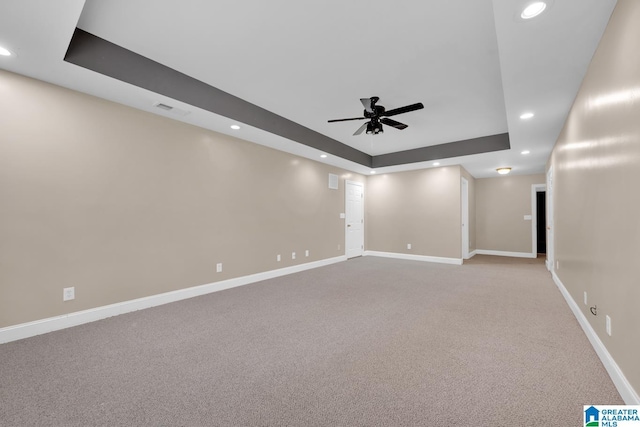 unfurnished room featuring light carpet, a raised ceiling, and ceiling fan