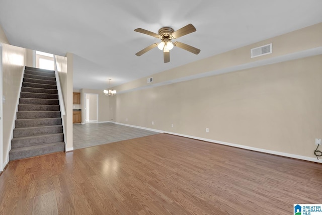 unfurnished living room featuring hardwood / wood-style floors and ceiling fan with notable chandelier