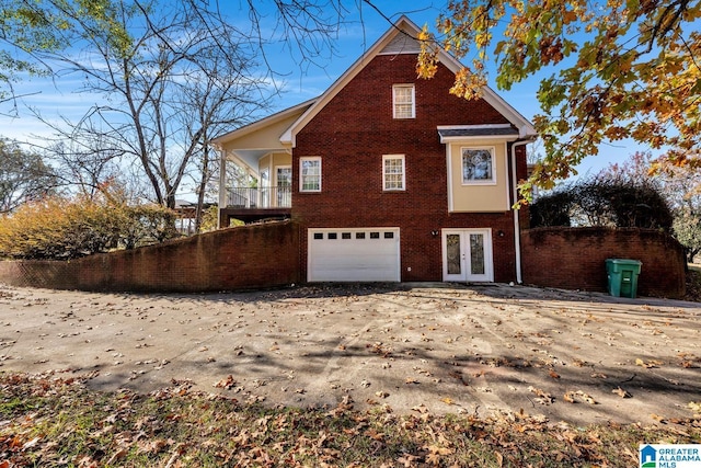 view of side of home with french doors, a balcony, and a garage