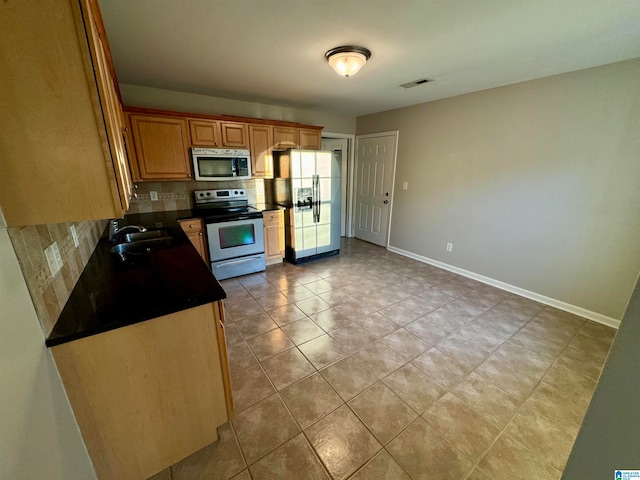 kitchen featuring backsplash, sink, light tile patterned flooring, and appliances with stainless steel finishes