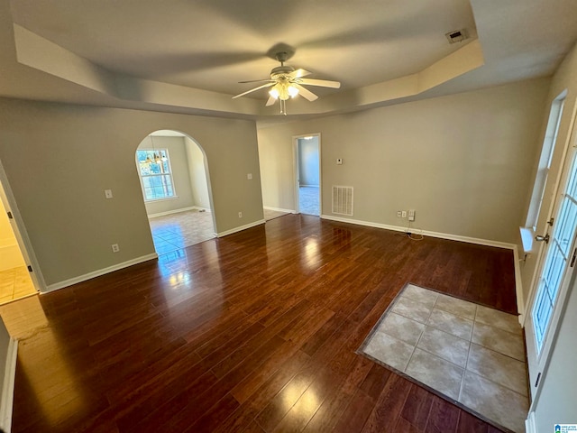 empty room featuring hardwood / wood-style floors, a tray ceiling, and ceiling fan