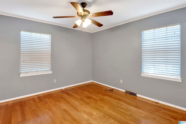 empty room featuring ornamental molding, light wood-type flooring, ceiling fan, and a healthy amount of sunlight