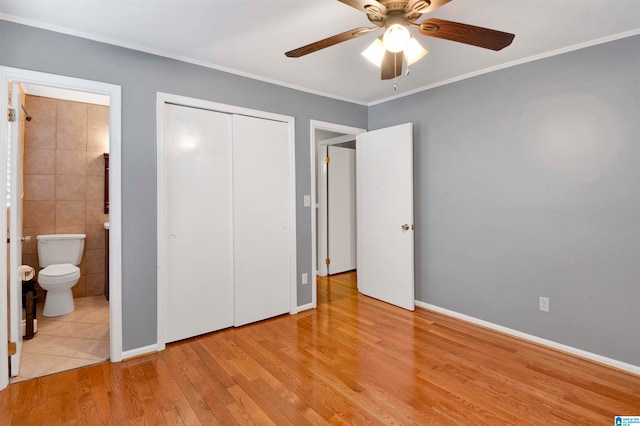 unfurnished bedroom with ensuite bath, ceiling fan, light wood-type flooring, ornamental molding, and a closet