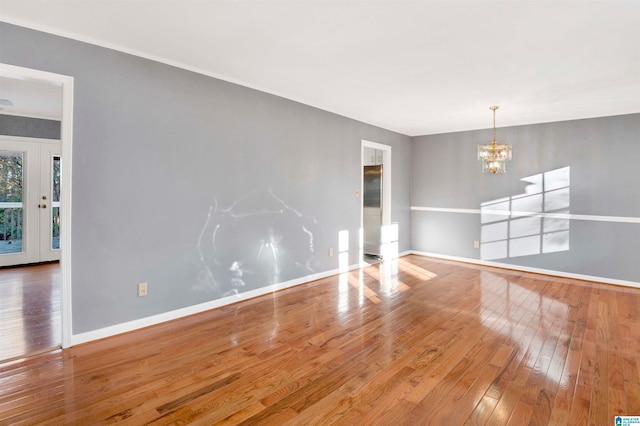 spare room with an inviting chandelier and hardwood / wood-style flooring