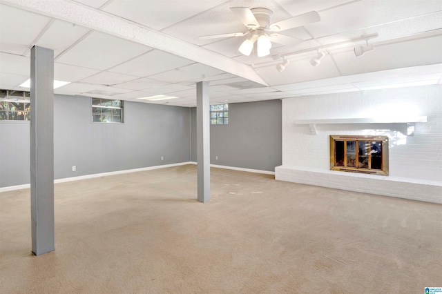 basement with light colored carpet, a brick fireplace, and ceiling fan