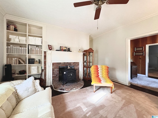 living room featuring a wood stove, ceiling fan, carpet floors, and ornamental molding