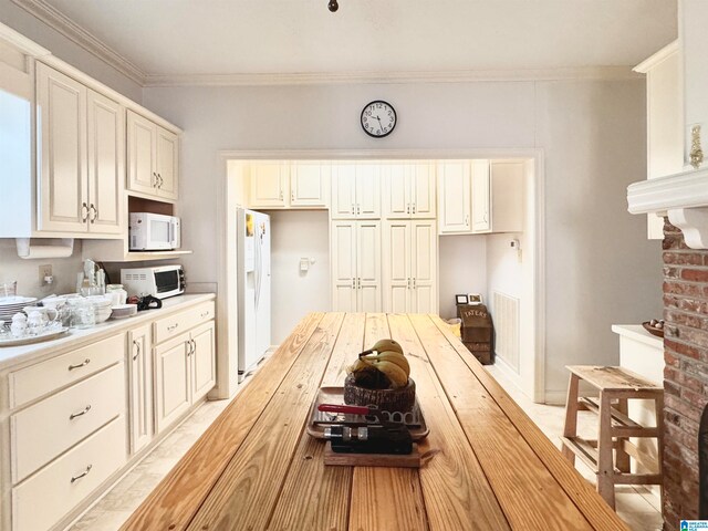 kitchen with cream cabinetry, white appliances, and crown molding