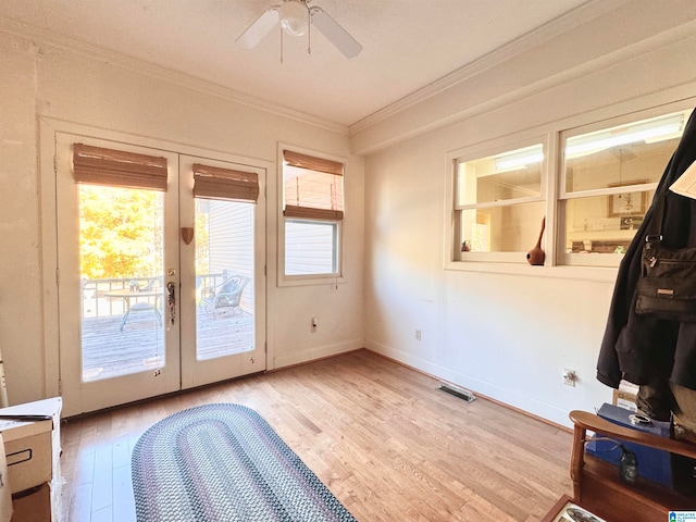 doorway with french doors, light wood-type flooring, crown molding, and a healthy amount of sunlight