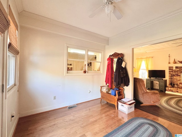 interior space with a fireplace, light wood-type flooring, ceiling fan, and ornamental molding