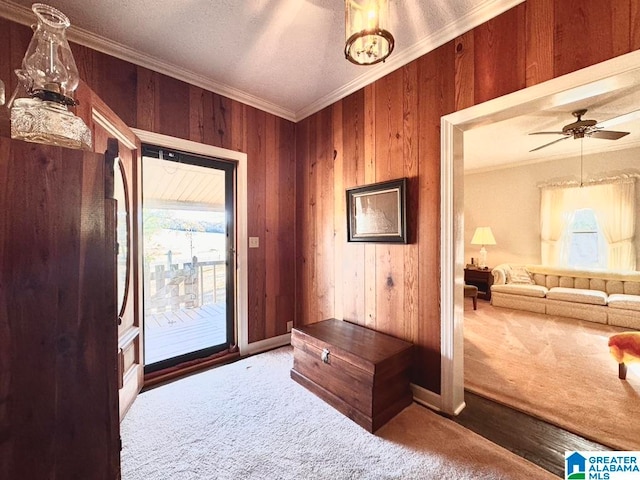 entryway featuring crown molding, carpet floors, wood walls, and ceiling fan