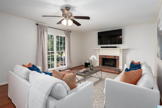 living room with ceiling fan, light hardwood / wood-style flooring, crown molding, a textured ceiling, and a fireplace