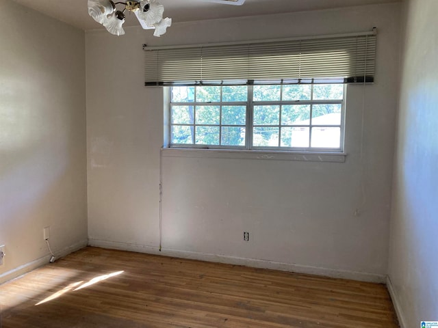 empty room with a notable chandelier and hardwood / wood-style flooring