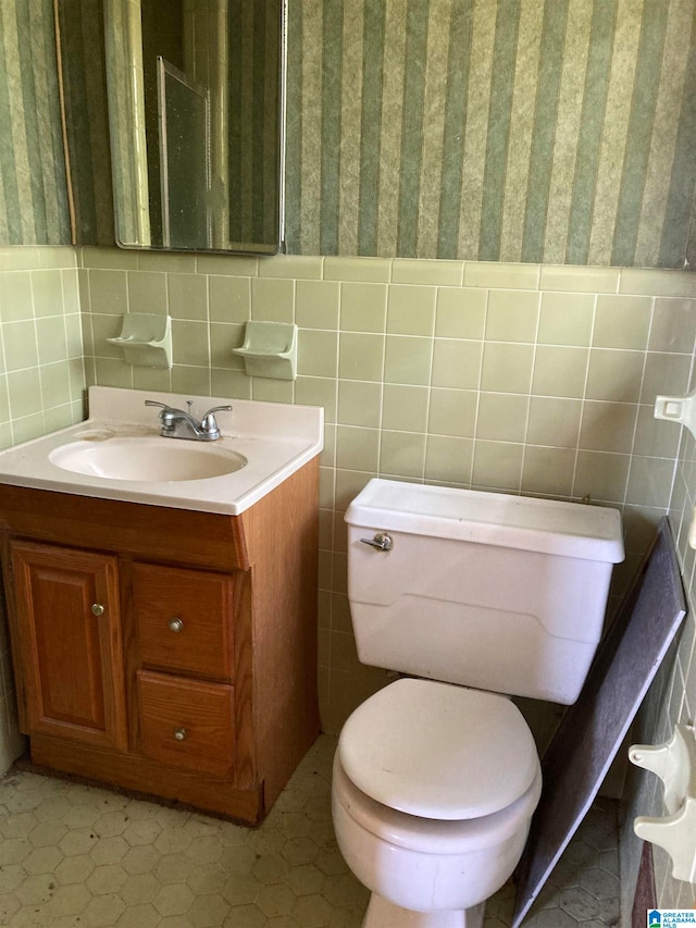 bathroom with tile patterned floors, vanity, tile walls, and toilet