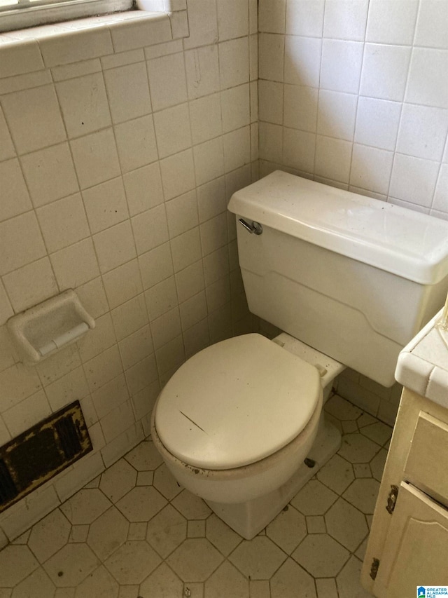 bathroom with tile patterned flooring, tile walls, and toilet