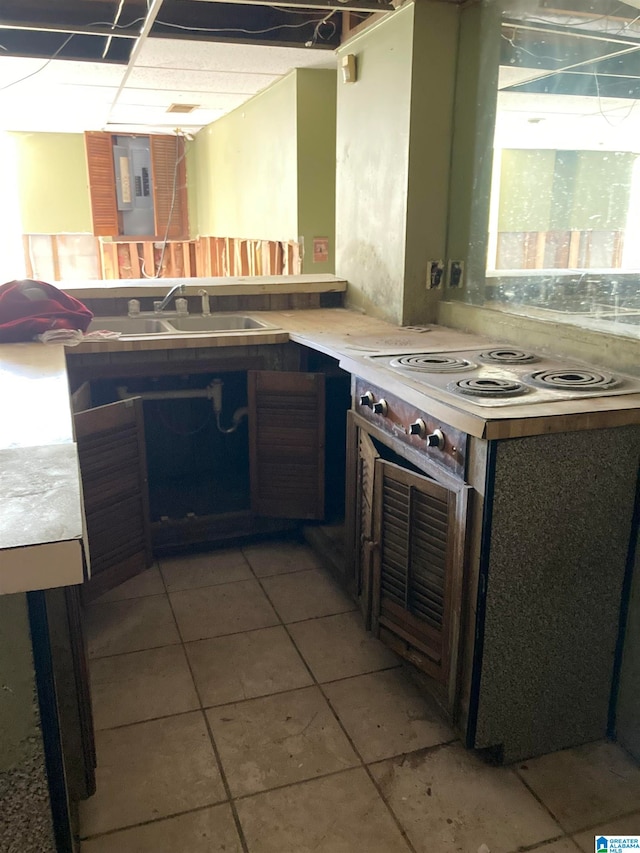 kitchen featuring electric range, light tile patterned floors, and sink