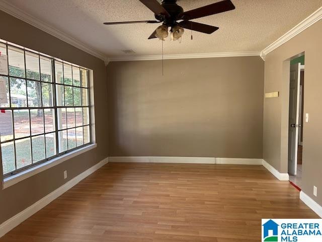 empty room with a textured ceiling, hardwood / wood-style flooring, and crown molding