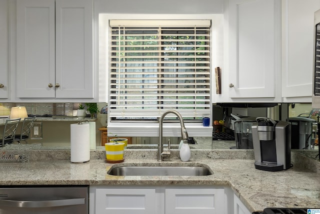 kitchen featuring dishwasher, white cabinets, light stone counters, and sink