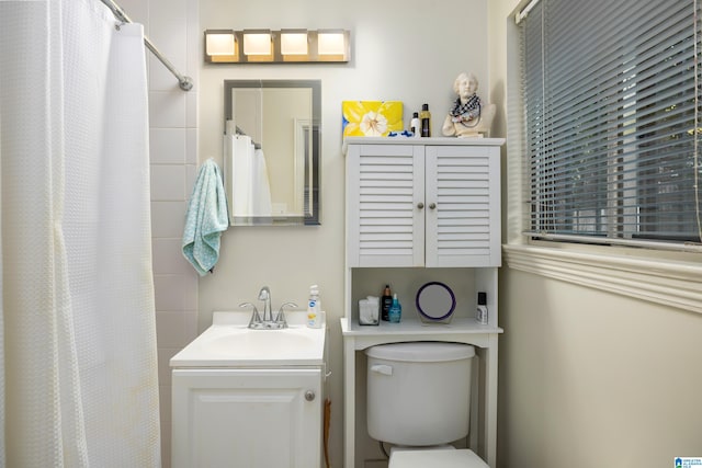 bathroom featuring toilet, vanity, and walk in shower