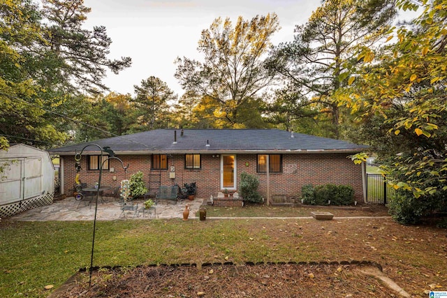 back of house featuring a shed, a yard, and a patio