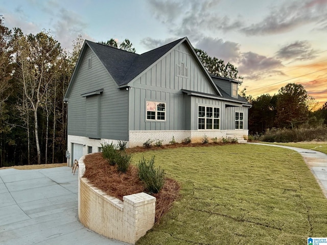 9225 Jardin Cir, Leeds, AL 35094 - property exterior at dusk featuring board and batten siding, a garage, a lawn, roof with shingles, and driveway
