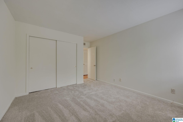 unfurnished bedroom with light carpet and a closet