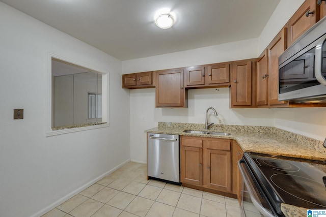 kitchen with light stone countertops, light tile patterned floors, stainless steel appliances, and sink