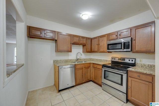 kitchen featuring light stone countertops, sink, light tile patterned flooring, and stainless steel appliances