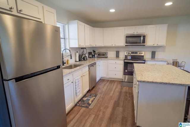 kitchen with sink, light stone countertops, appliances with stainless steel finishes, dark hardwood / wood-style flooring, and white cabinetry