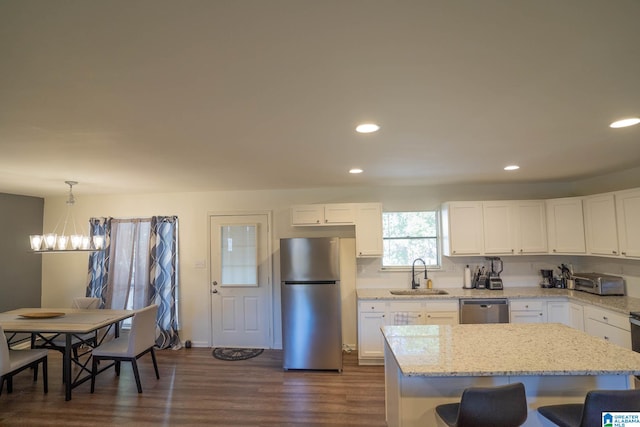 kitchen with stainless steel appliances, dark wood-type flooring, sink, an inviting chandelier, and hanging light fixtures