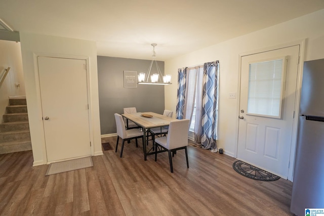 dining area with hardwood / wood-style floors and an inviting chandelier