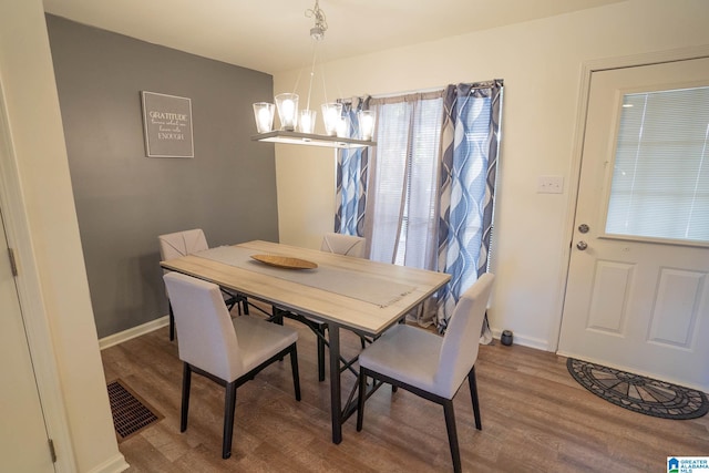 dining space with hardwood / wood-style floors and a chandelier