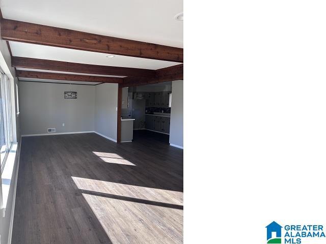 unfurnished living room with beam ceiling and dark hardwood / wood-style flooring