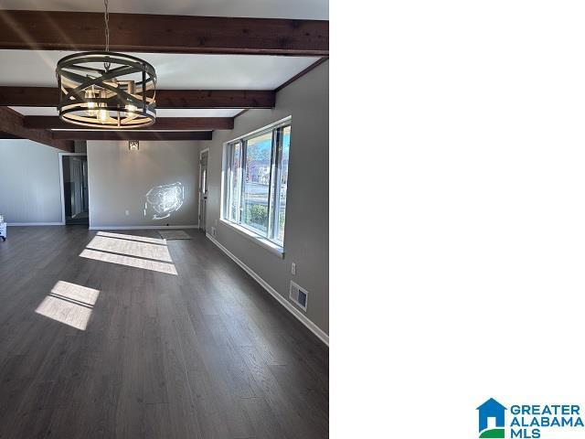 interior space featuring beam ceiling, dark wood-type flooring, and a notable chandelier