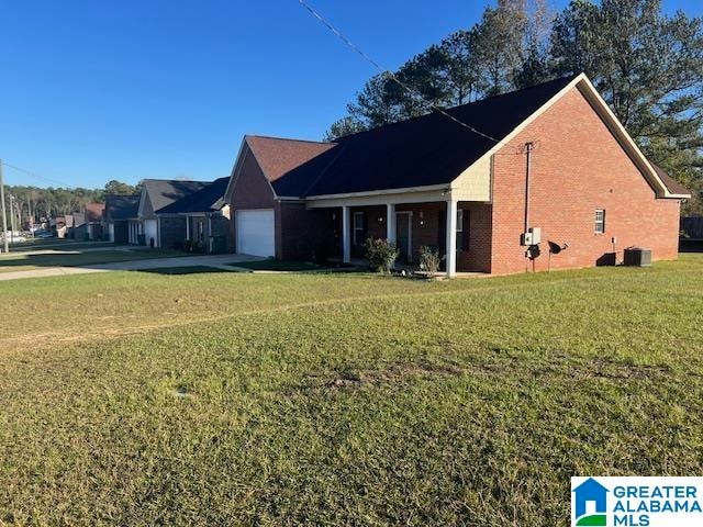 view of front of property with central AC, a garage, and a front lawn