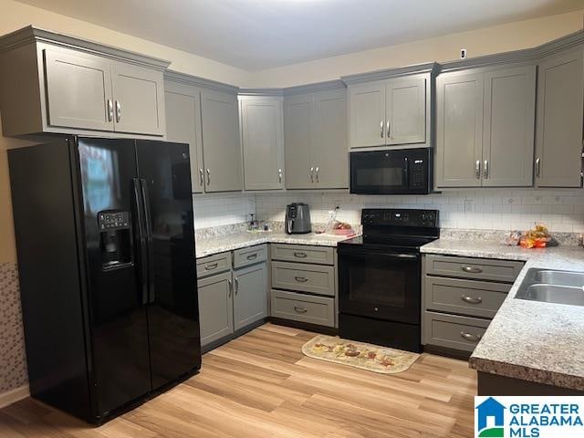 kitchen with backsplash, sink, black appliances, light hardwood / wood-style flooring, and gray cabinets