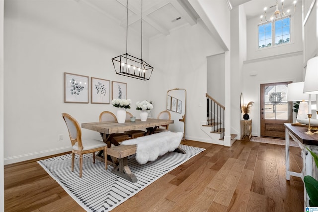 dining area featuring hardwood / wood-style floors, beam ceiling, and a high ceiling