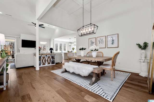 dining space with ceiling fan, beam ceiling, wood-type flooring, and high vaulted ceiling