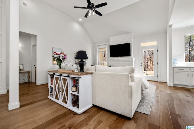 living room with ceiling fan, lofted ceiling, ornamental molding, and light hardwood / wood-style flooring