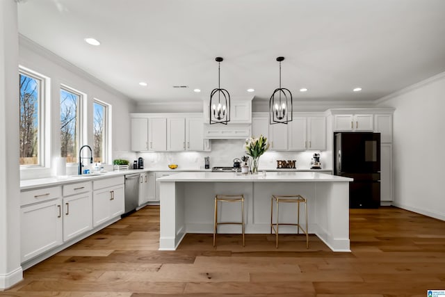 kitchen with white cabinets, appliances with stainless steel finishes, light hardwood / wood-style flooring, and a kitchen island