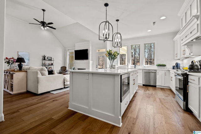 kitchen featuring pendant lighting, light hardwood / wood-style floors, a center island with sink, white cabinets, and appliances with stainless steel finishes