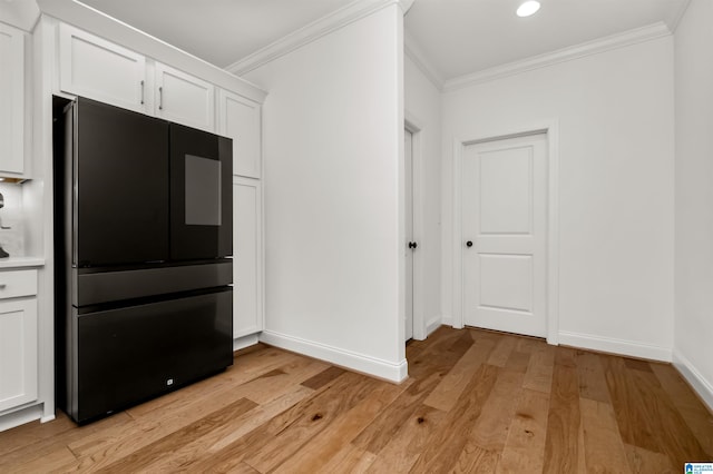 kitchen featuring crown molding, black refrigerator, white cabinets, and light wood-type flooring