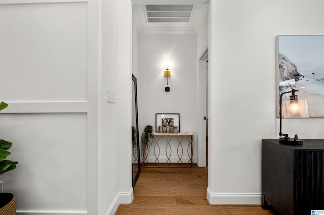 hallway with light wood-type flooring and ornamental molding