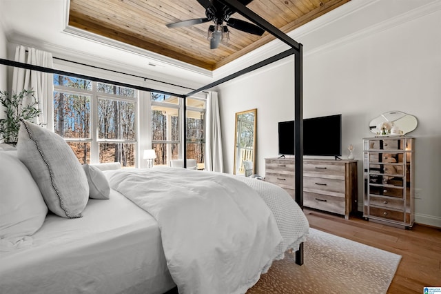 bedroom with ornamental molding, wood ceiling, a raised ceiling, ceiling fan, and hardwood / wood-style floors