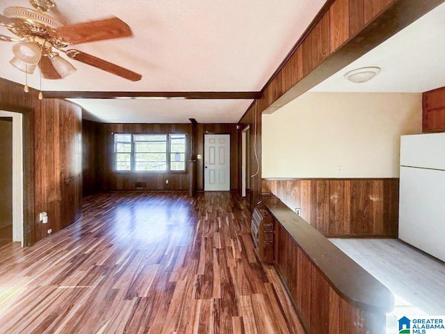 unfurnished room featuring dark hardwood / wood-style floors, ceiling fan, a textured ceiling, and wooden walls