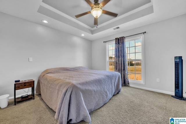 bedroom featuring ceiling fan, a raised ceiling, and light carpet